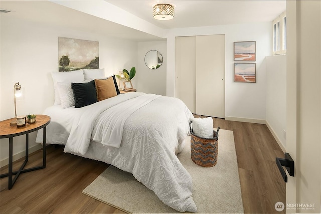 bedroom featuring visible vents, wood finished floors, a closet, and baseboards