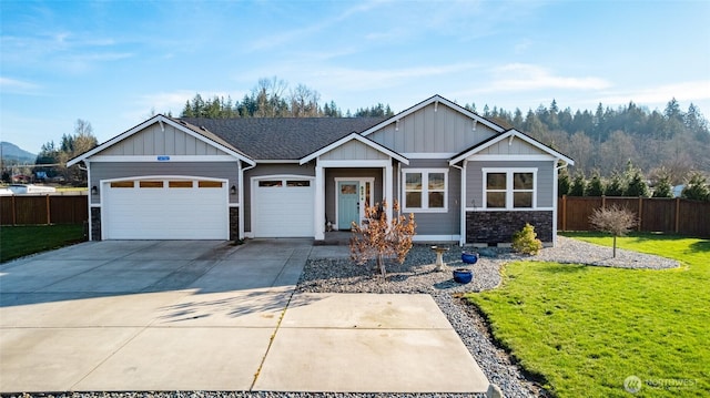 view of front of house featuring a garage, fence, driveway, board and batten siding, and a front yard