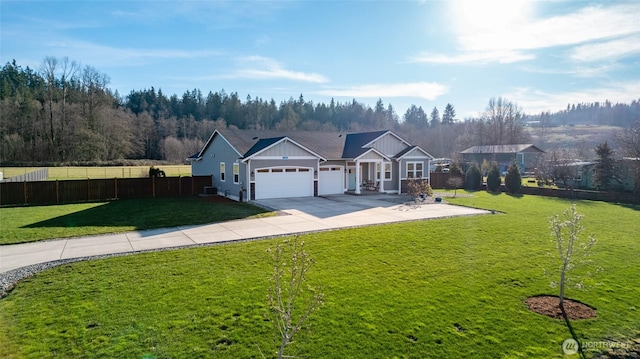 view of front facade with a front lawn, fence, driveway, and an attached garage