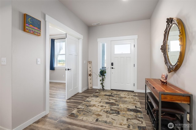 foyer with wood finished floors, visible vents, and baseboards