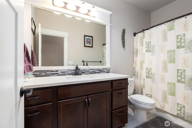 bathroom with vanity, toilet, and decorative backsplash