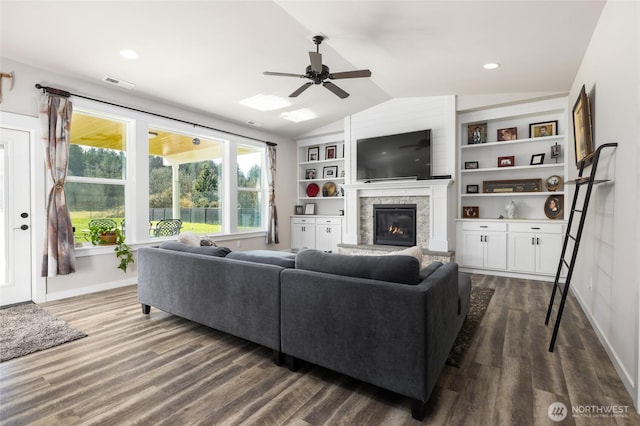 living room with lofted ceiling, a stone fireplace, dark wood-style floors, and visible vents