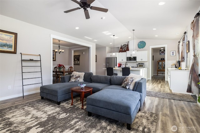 living room with recessed lighting, ceiling fan with notable chandelier, wood finished floors, baseboards, and vaulted ceiling