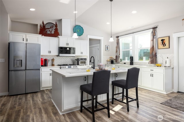 kitchen with white cabinetry, vaulted ceiling, light countertops, stainless steel refrigerator with ice dispenser, and dark wood finished floors