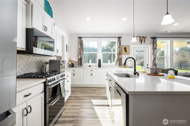 kitchen featuring stainless steel appliances, a wealth of natural light, a sink, and backsplash