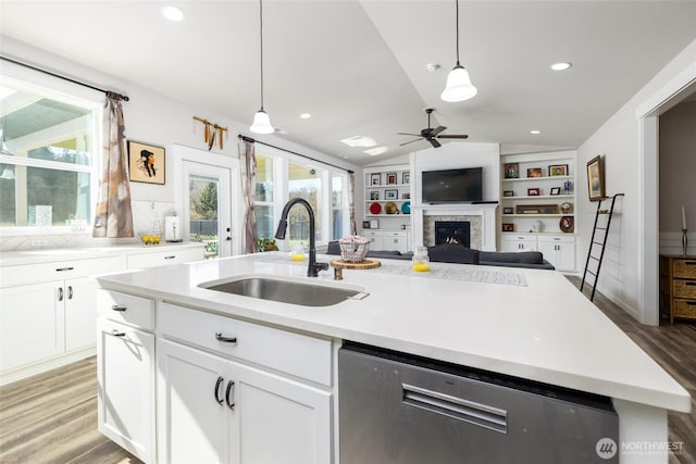 kitchen featuring a center island with sink, lofted ceiling, a sink, light wood-type flooring, and stainless steel dishwasher