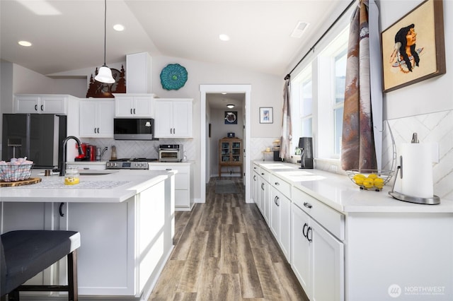 kitchen with lofted ceiling, light countertops, black fridge with ice dispenser, a sink, and wood finished floors