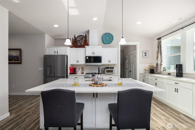 kitchen with lofted ceiling, light wood-style flooring, stainless steel microwave, white cabinetry, and refrigerator with ice dispenser