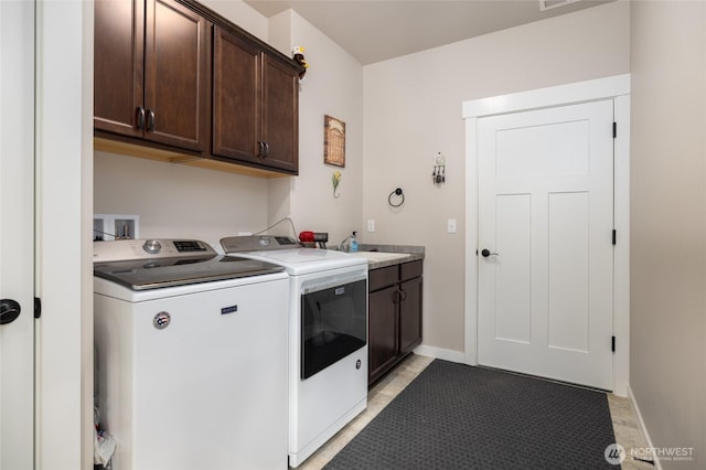 clothes washing area with separate washer and dryer, cabinet space, and baseboards