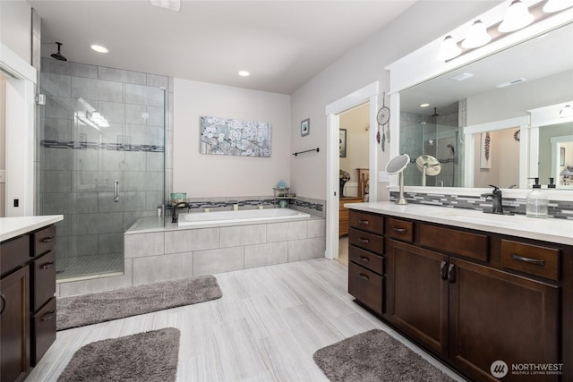 bathroom with recessed lighting, a garden tub, a shower stall, and vanity