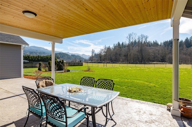 view of patio / terrace featuring a fenced backyard, a rural view, a mountain view, and outdoor dining space