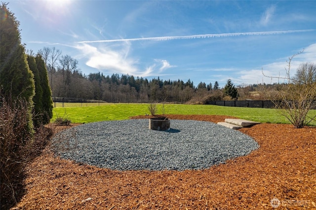 view of yard featuring a wooded view and fence