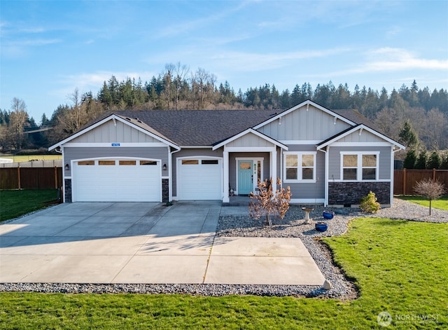 view of front facade with an attached garage, fence, driveway, stone siding, and a front lawn