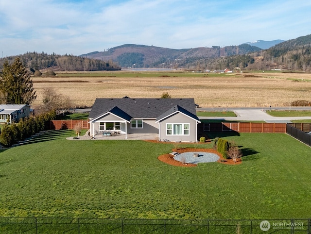 back of house featuring a patio area, a fenced backyard, a mountain view, and a lawn