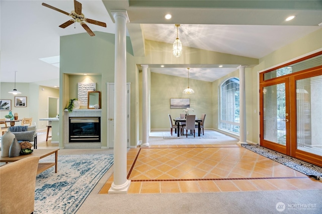 carpeted foyer with french doors, lofted ceiling, a glass covered fireplace, tile patterned flooring, and ornate columns