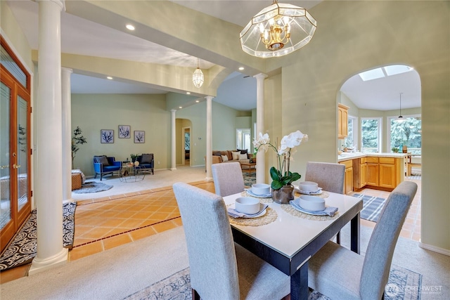 dining room with arched walkways, decorative columns, lofted ceiling, recessed lighting, and light colored carpet