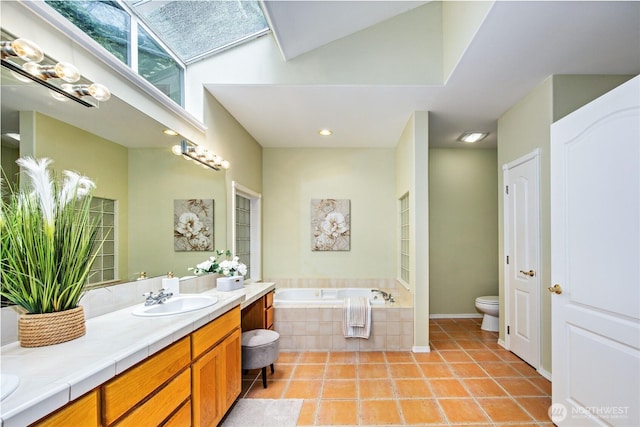 bathroom with double vanity, toilet, a sink, tile patterned flooring, and a bath