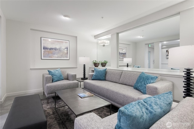 living area with decorative columns and baseboards