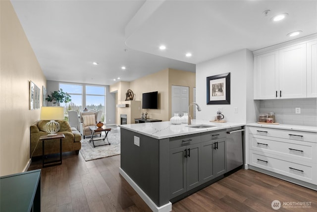 kitchen featuring dark wood finished floors, white cabinetry, a sink, dishwasher, and a peninsula