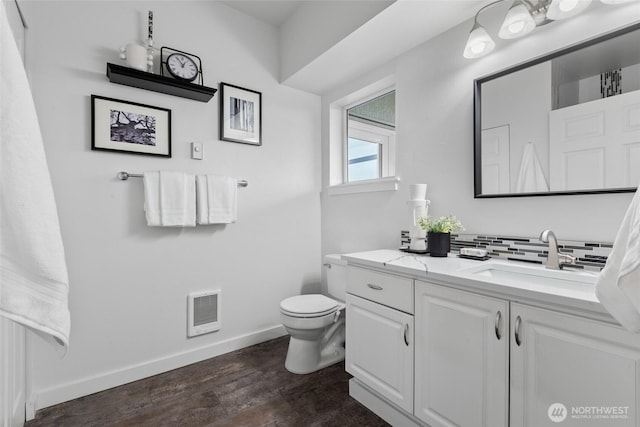 bathroom featuring baseboards, visible vents, decorative backsplash, toilet, and wood finished floors