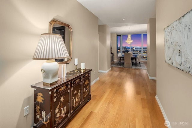 corridor featuring light wood-style floors, baseboards, and a wall of windows