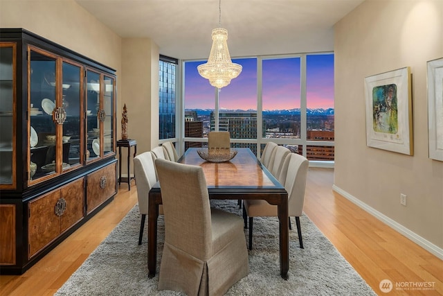 dining area featuring a chandelier, floor to ceiling windows, baseboards, and wood finished floors