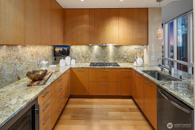 kitchen featuring wine cooler, light stone counters, a sink, appliances with stainless steel finishes, and light wood finished floors