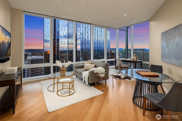 living area featuring a wall of windows, baseboards, and wood finished floors