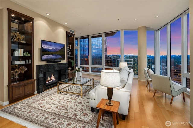 living room with floor to ceiling windows, a premium fireplace, and wood finished floors