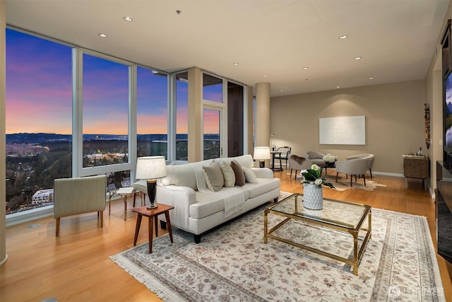 living area featuring a wall of windows, recessed lighting, baseboards, and wood finished floors