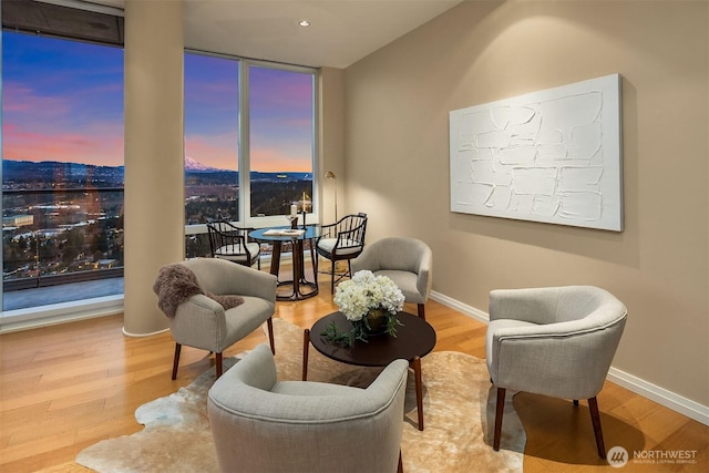 sitting room featuring floor to ceiling windows, baseboards, and wood finished floors