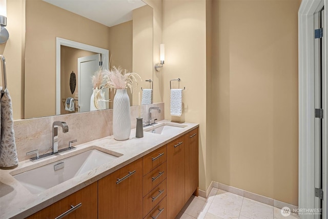 full bathroom featuring double vanity, baseboards, and a sink