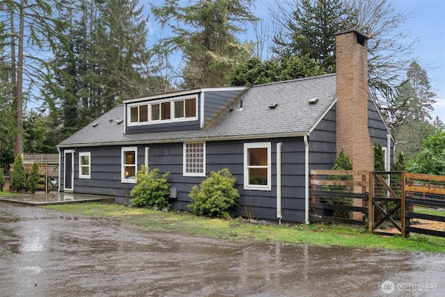 exterior space featuring a chimney, fence, and roof with shingles