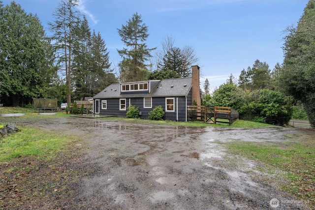 view of front of property with a trampoline, a chimney, and a wooden deck