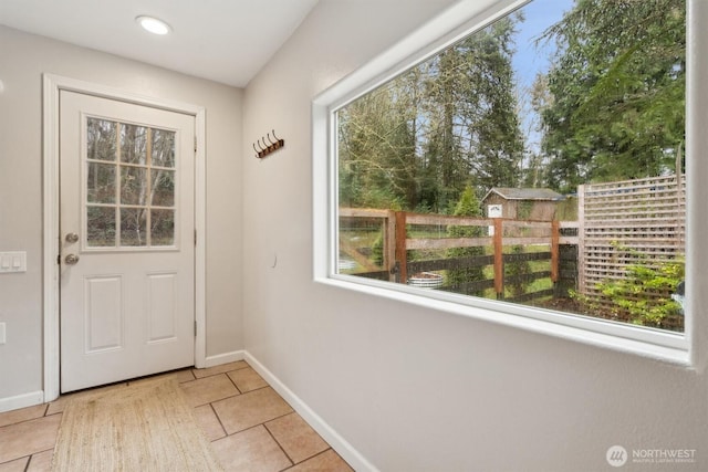 doorway with light tile patterned flooring and baseboards