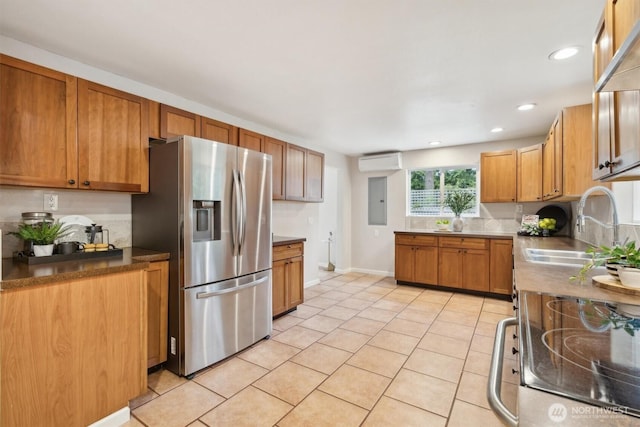 kitchen with a sink, stainless steel refrigerator with ice dispenser, electric range oven, brown cabinetry, and a wall mounted air conditioner