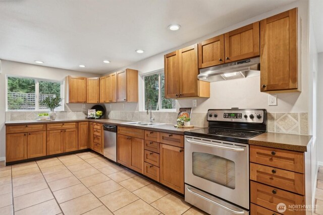 kitchen featuring light tile patterned floors, appliances with stainless steel finishes, under cabinet range hood, a sink, and recessed lighting