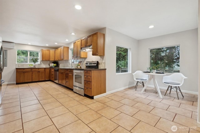 kitchen featuring recessed lighting, under cabinet range hood, stainless steel appliances, baseboards, and brown cabinetry