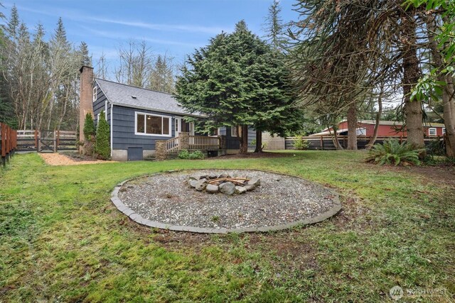 view of yard featuring a fire pit, a deck, and a fenced backyard