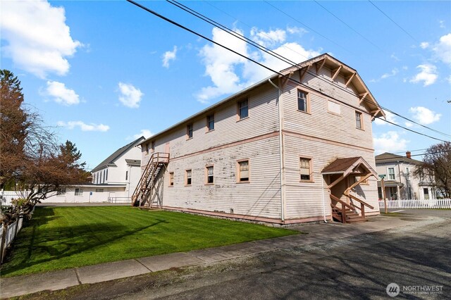 view of home's exterior featuring entry steps, fence, and a lawn