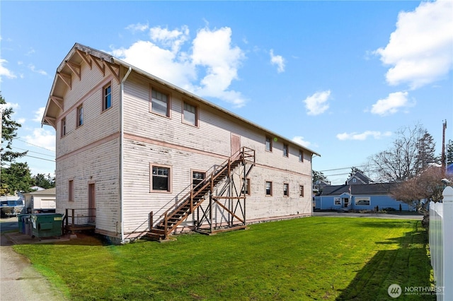 rear view of house with fence, stairway, and a yard