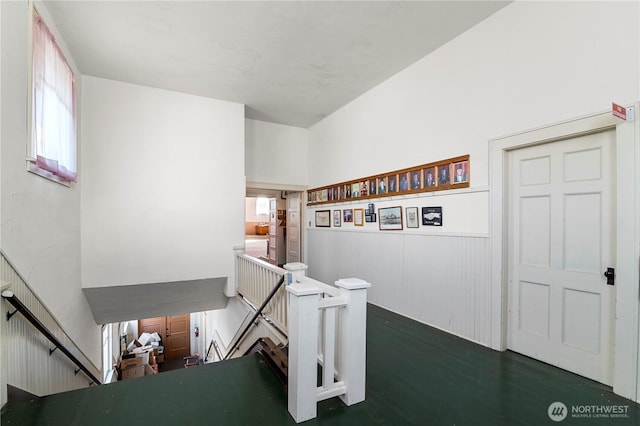 stairs with a healthy amount of sunlight and a wainscoted wall