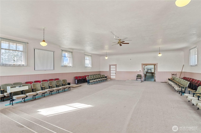 interior space featuring a ceiling fan and a wainscoted wall