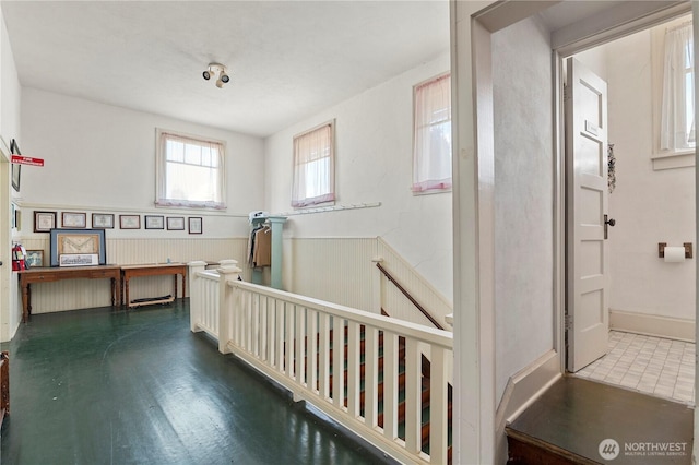 interior space with a wainscoted wall and an upstairs landing