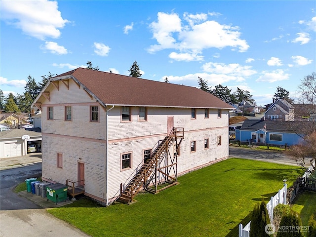 back of property featuring a residential view, stairs, fence, and a yard