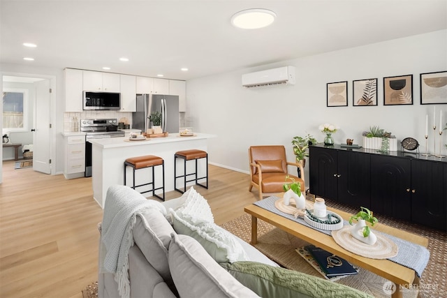 living area with light wood-type flooring, baseboards, an AC wall unit, and recessed lighting