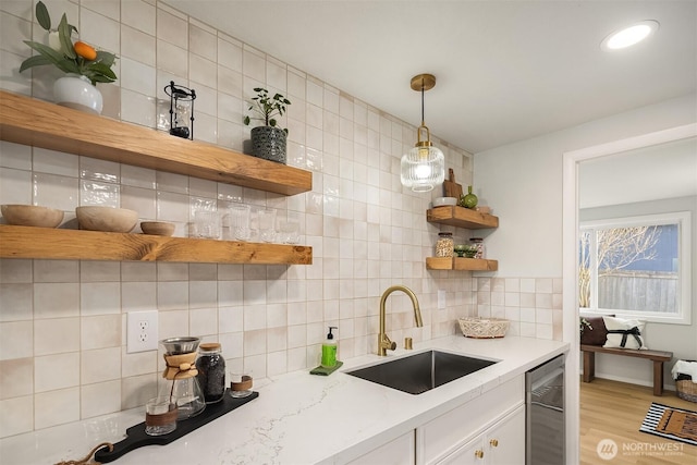 kitchen featuring light stone counters, a sink, white cabinets, backsplash, and open shelves