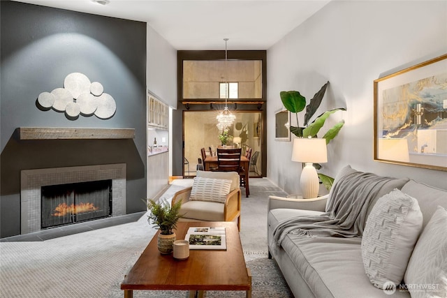 living room with an inviting chandelier, carpet, a towering ceiling, and a lit fireplace