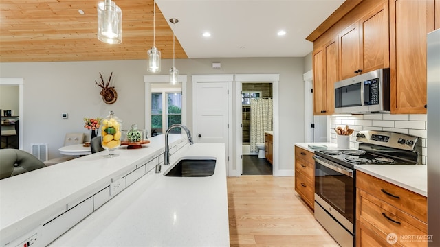 kitchen with stainless steel appliances, tasteful backsplash, light countertops, visible vents, and a sink