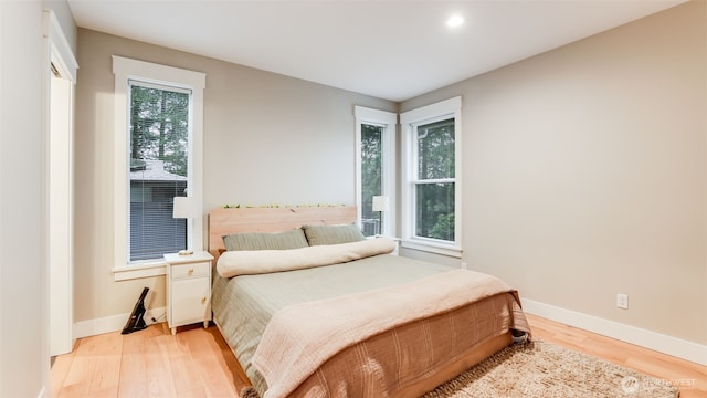 bedroom with light wood-type flooring, multiple windows, and baseboards